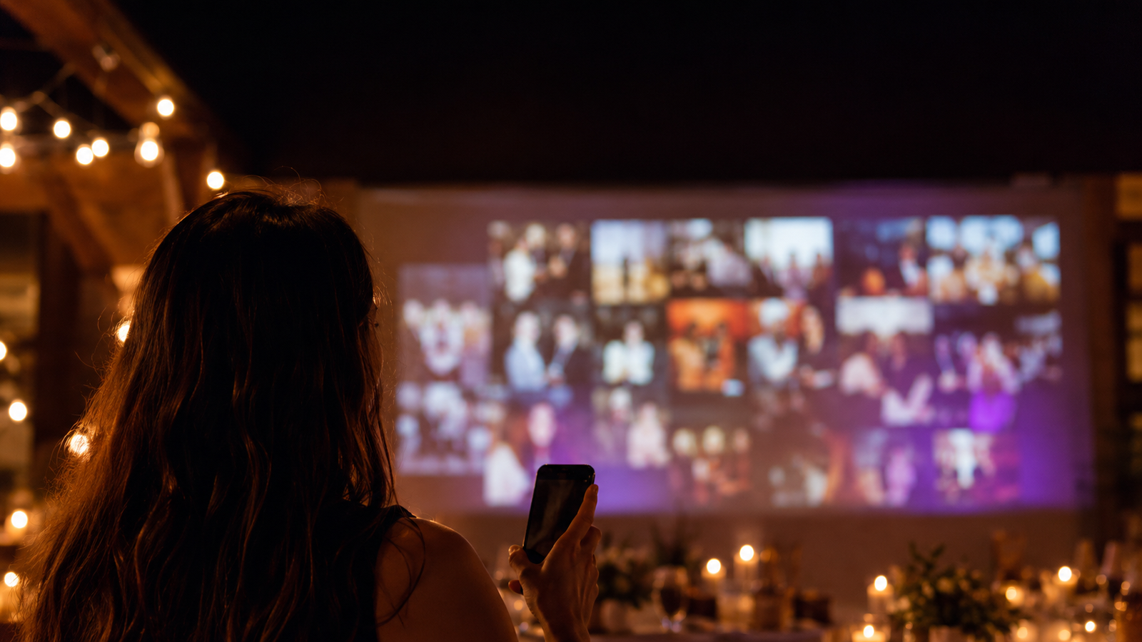 Happy guests at a party in front of a screen showing a live photo wall of the night's pictures